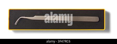 curved metal tweezers inside black foam case isolated white background, stainless steel jewelry tool in yellow plastic box, top view Stock Photo