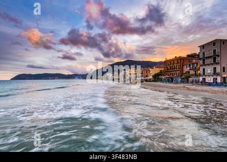 Italy Liguria At the last light of the day the houses of Alassio overlook the sea while in the background you can see the turtle shape of the Gallinar Stock Photo