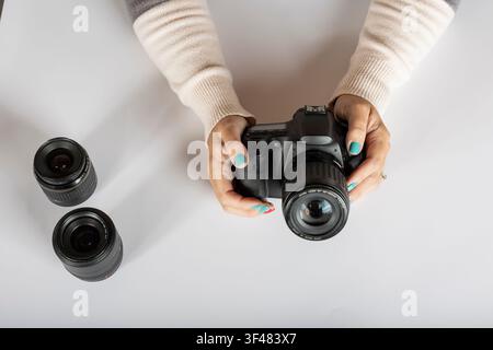 Holding DSLR Camera with Interchangeable Lenses on White Surface Stock Photo
