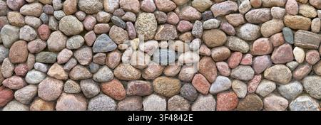Wide wall made of large, variously colored pebble stones Stock Photo