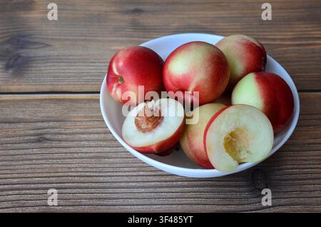 Fresh Nectarines in a Bowl on a Wooden Table copy space Stock Photo