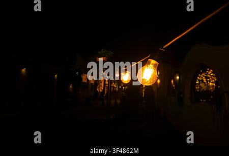 String lights illuminate a dark outdoor setting. The warm glow creates a cozy atmosphere, enhancing the ambiance of the night scene. Stock Photo