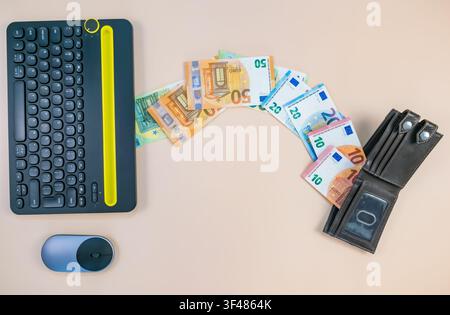 Top view of a black keyboard and mouse with Euro banknotes flowing into a wallet on a pink background, symbolizing digital online income concept. Stock Photo
