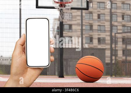 Smartphone mockup in hand with basketball on court Stock Photo