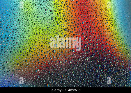 Vibrant water droplets cover a neon-colored surface, creating a mesmerizing interplay of light and color. Perfect for cosmetic, design, and abstract-t Stock Photo
