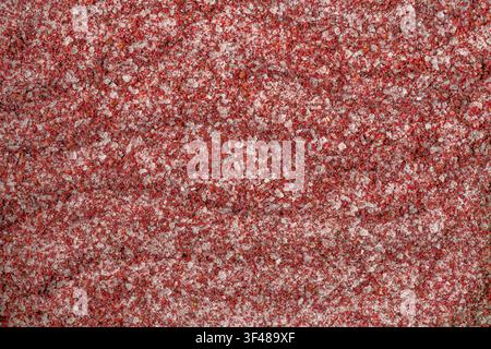 Close-up macro image showcasing vibrant pomegranate salt crystals. The red hues and granular texture create an intricate and colorful background perfe Stock Photo
