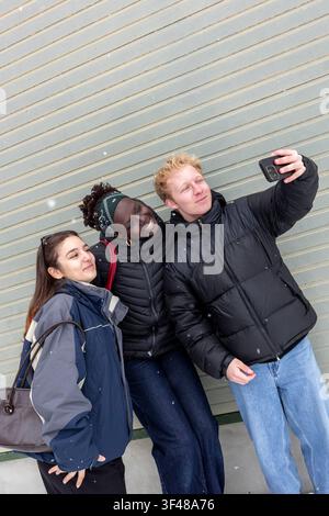 A group of friends enjoying a snowy day, capturing their fun tourist adventure. They are dressed warmly in winter clothing and surrounded by a backdro Stock Photo