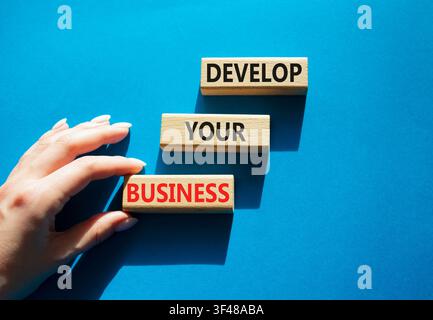 Develop your business symbol. Concept words develop your business on wooden blocks arranged as steps. Businessman hand arranging wooden blocks. Busine Stock Photo