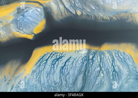 Vibrant abstract nature texture resembling an aerial landscape, with flowing blue and gold mineral-like patterns and dark river shapes, ideal for wall Stock Photo