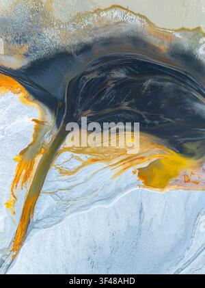 Vibrant abstract nature texture forming a fluid landscape of dark slate, gold, and icy blue tones. Organic marbling patterns create a modern wallpaper Stock Photo