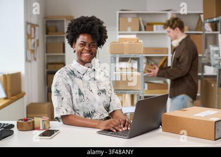Portrait of Black Woman Managing Online Orders in Packing Workspace Stock Photo