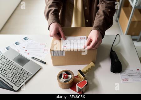 Adult Worker Applying Shipping Label on Parcel for Online Order Stock Photo