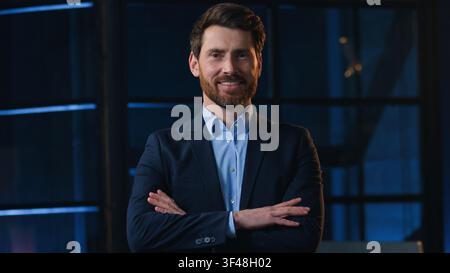 Confident portrait Caucasian mature business man crossing hands smiling looking at camera indoors at night evening office adult middle-aged happy Stock Photo