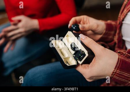Close-up of female hands opening case with compact wireless microphones. Shallow depth of field focuses on technology for vlogging, interviews, or Stock Photo