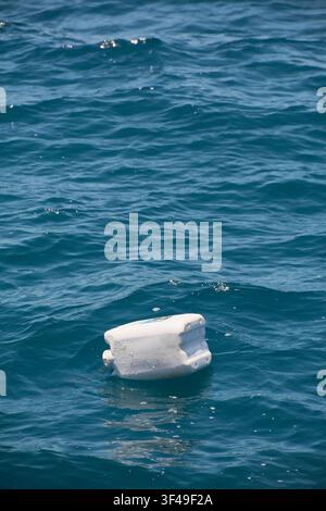 A white plastic jerrycan floats adrift on the deep blue sea, illustrating global environmental issues regarding marine debris. Stock Photo