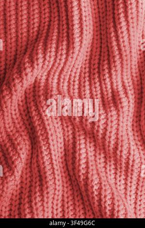 Close up, macro of crumpled red colored knitted fabric. Cloth with visible wrinkles, folds and soft waves. Soft wool material texture with detailed st Stock Photo