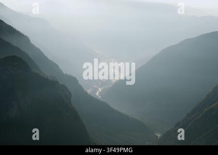 Morning mist fills the valley surrounding Cortina d'Ampezzo beneath layered mountain ridges. Atmospheric Dolomite landscape with soft light and alpine scenery Stock Photo