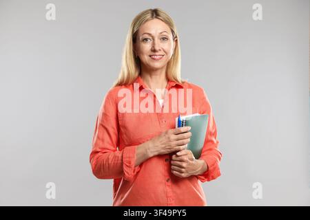 Teacher with notebooks and pen on light grey background Stock Photo