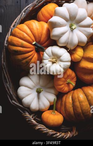 Close-up of wicker basket full of orange pumpkins in various sizes for fall harvest. Seasonal holiday background perfect for Thanksgiving or Halloween decor Stock Photo
