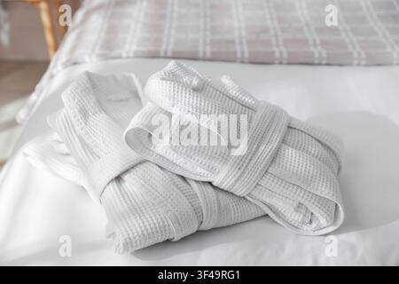 Two clean bathrobes on bed indoors, closeup Stock Photo
