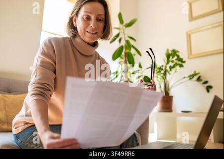 Content middle aged female entrepreneur reading report Stock Photo