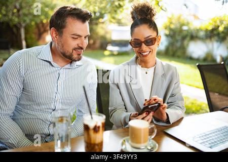 Young business colleagues collaborating at outdoor cafe, sharing ideas over coffee Stock Photo