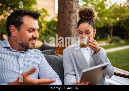 Business colleagues discussing project ideas using digital tablet outdoors Stock Photo