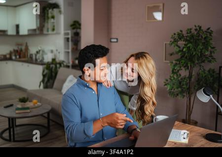 Couple working from home collaborating on laptop in living room Stock Photo