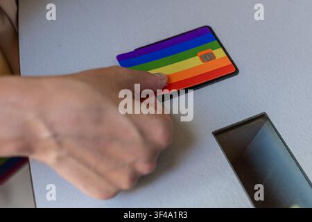 Hand inserting rainbow credit card for lgbtq plus pride payment Stock Photo