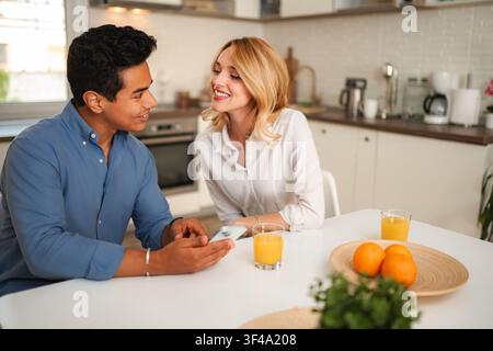 Happy couple sharing morning breakfast and using smartphone Stock Photo