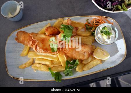 Fried fish with fries and lemon garnish on a restaurant plate Stock ...