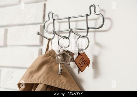 Rack with keys from house on light wall, closeup Stock Photo