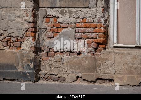 Weathered brick wall with damaged plaster and exposed masonry texture Stock Photo