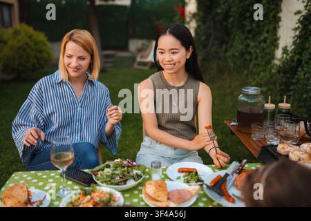 Diverse friends enjoying outdoor barbecue dinner party together Stock Photo