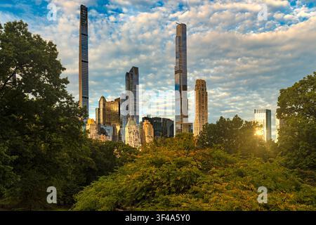 Sunrise view of midtown Manhattan skyline from Central Park featuring tall slender skyscrapers along Billionaires Row Stock Photo