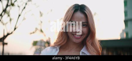 Young asian woman smiling, enjoying golden hour light Stock Photo