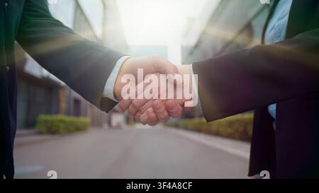 Greeting business handshake man woman shaking hands partnership success deal formal city outdoors office building close up handshaking partners Stock Photo