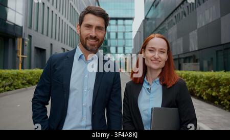 Portrait confident Caucasian business people man woman in city looking at camera downtown happy workers smiling businesswoman businessman corporate Stock Photo