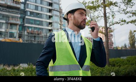 Caucasian man builder engineer in hardhat talking walkie talkie blueprints plan urban city development buildings electricity business engineering male Stock Photo