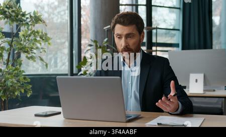 Caucasian businessman typing laptop speaking video call in office writing notes male manager HR employee entrepreneur CEO online meeting business man Stock Photo