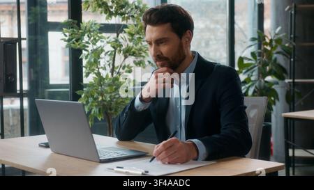 Successful busy Caucasian businessman typing on laptop in office writing notes professional adult male accountant business man guy manager employee Stock Photo