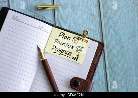 Plan Prioritize Progress Sticky Note on Leather Planner with Fountain Pen and Productivity Icons Stock Photo