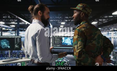 Army technicians in command center server room using artificial intelligence to detect cyber threats. Military data center experts use AI detection software to secure defense systems Stock Photo