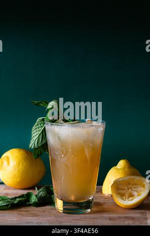 A lemonade drink with mint and lemons, wood table, green background Stock Photo