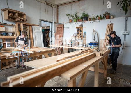 Craftsmanship, equality and teamwork, men and woman masters working together in restoration workshop Stock Photo