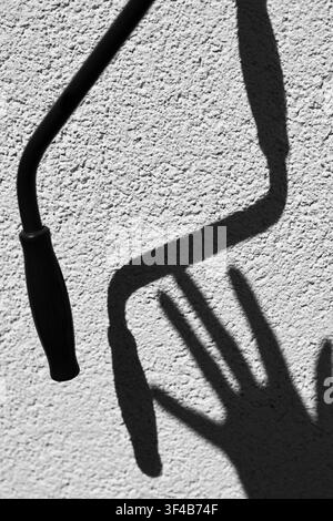 A hand casting dramatic shadow on textured wall in bright sunlight, minimalist outdoor concept Stock Photo