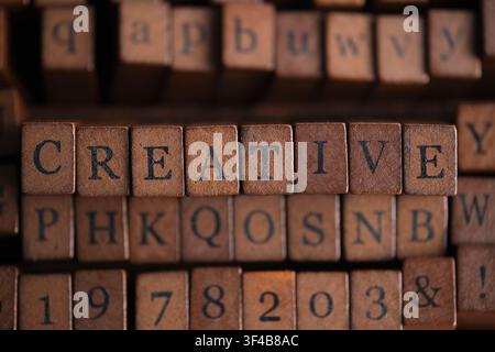 Word CREATIVE in vintage wooden letterpress blocks placed among various printing stamp types Stock Photo