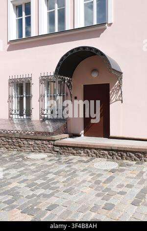Graphic summer shadows forged iron window bars exterior. Minimalist architectural lines on trendy pastel pink building facade with vintage entrance Stock Photo