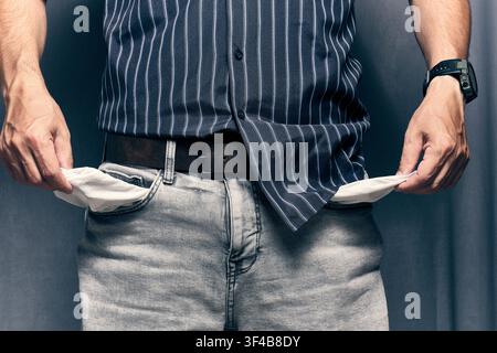 Man pulling out empty pockets from light grey jeans showing concept financial trouble or debt Stock Photo