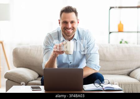 Young man drinking coffee and using laptop Stock Photo